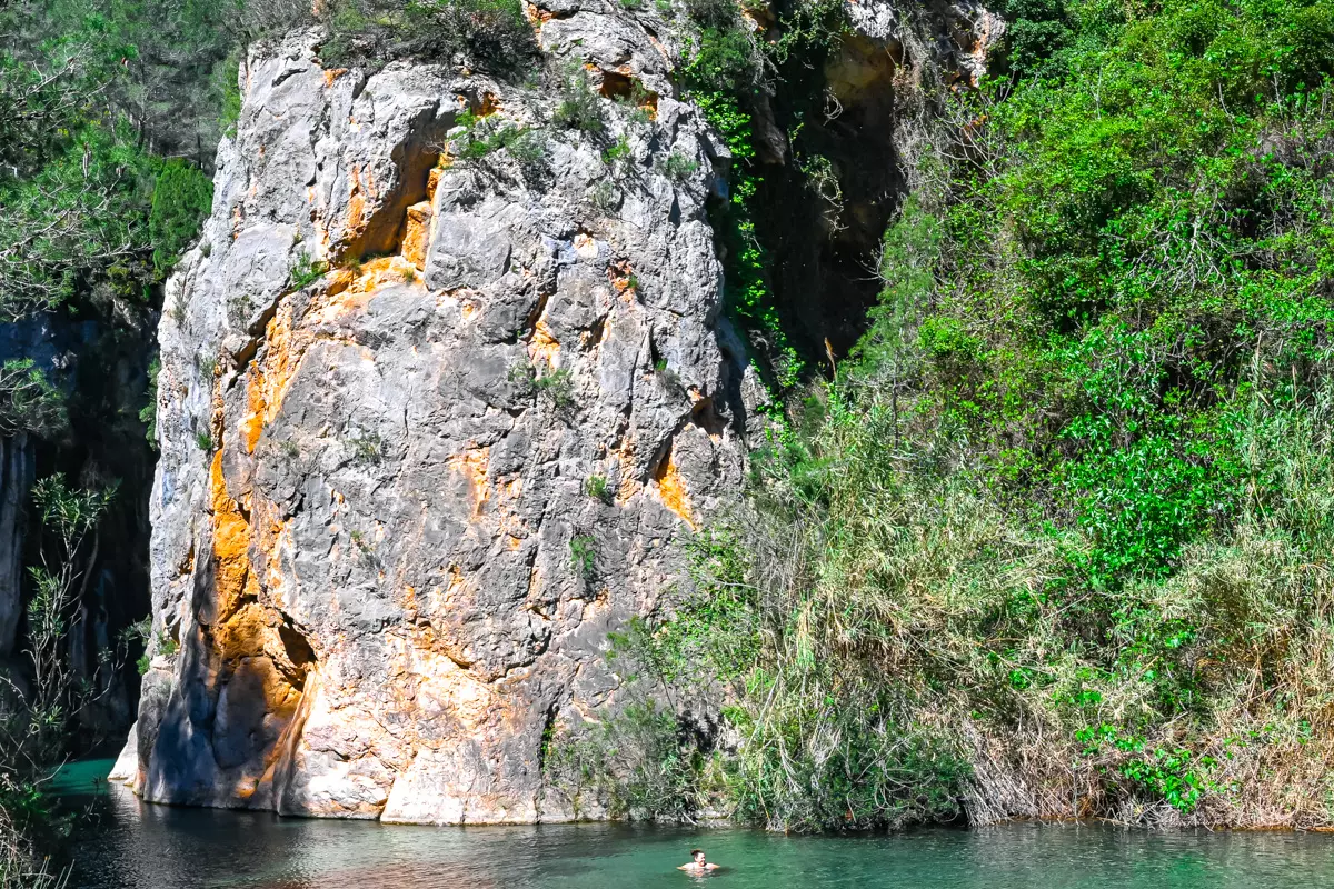 A swimmer enjoying the hot spring waters near the canyon wall.