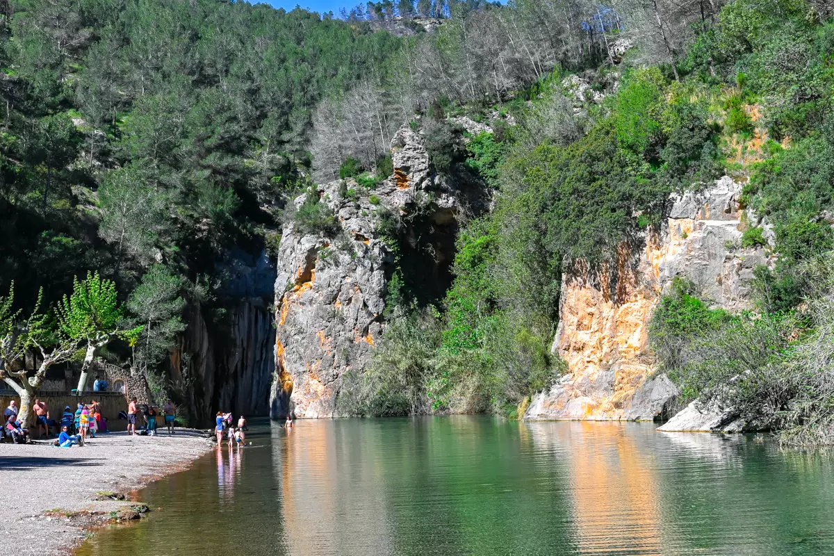 People relaxing along the riverbank at Montanejos Hot Springs.