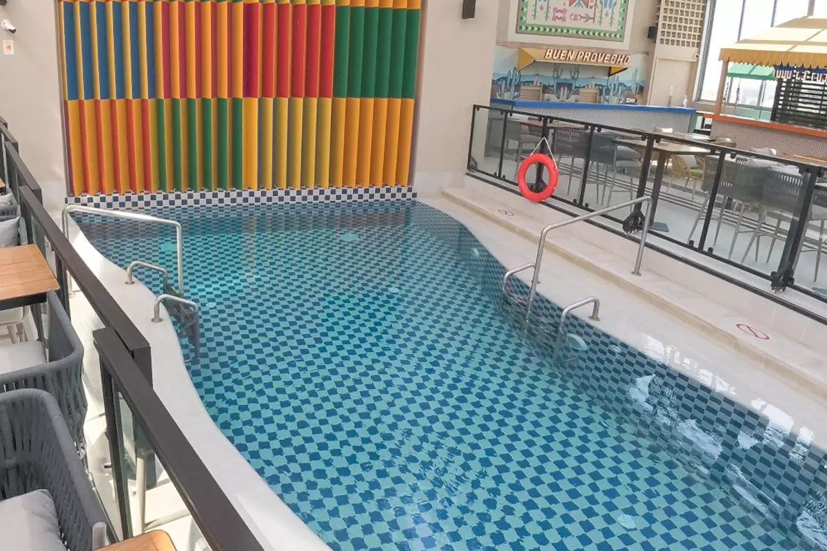 Rooftop swimming pool at DoubleTree by Hilton Doha – Old Town with patterned blue tiles, colorful wall décor, and nearby seating area