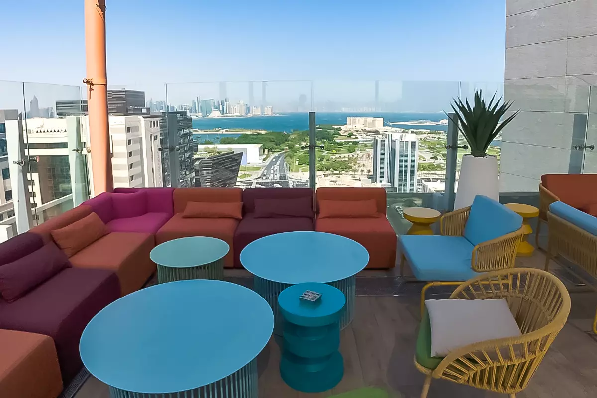 Rooftop lounge at DoubleTree by Hilton Doha – Old Town with colorful seating, outdoor tables, and panoramic views of the Doha skyline and waterfront
