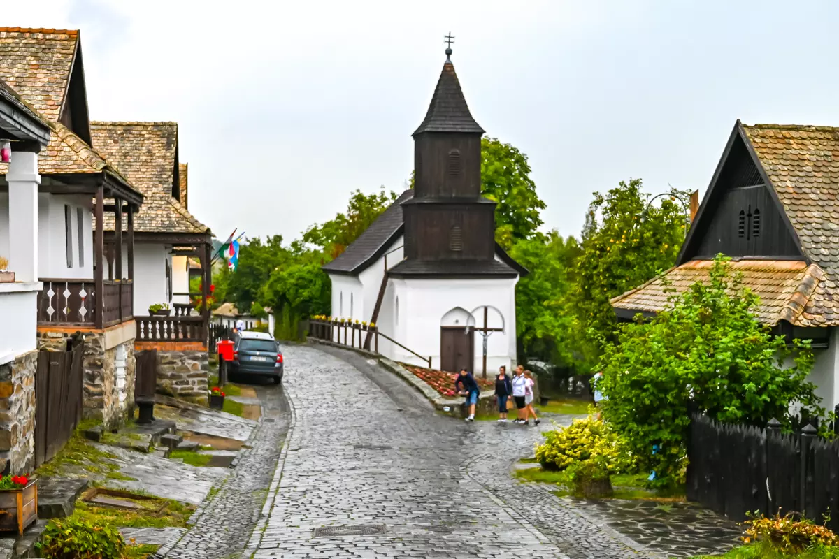 Wooden church in Hollókő, with a shingled tower and white walls.